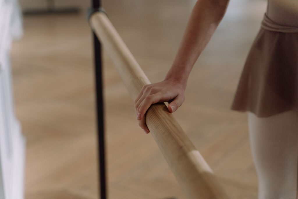 Elegant capture of a ballet dancer's hand on a barre, showcasing grace and focus.